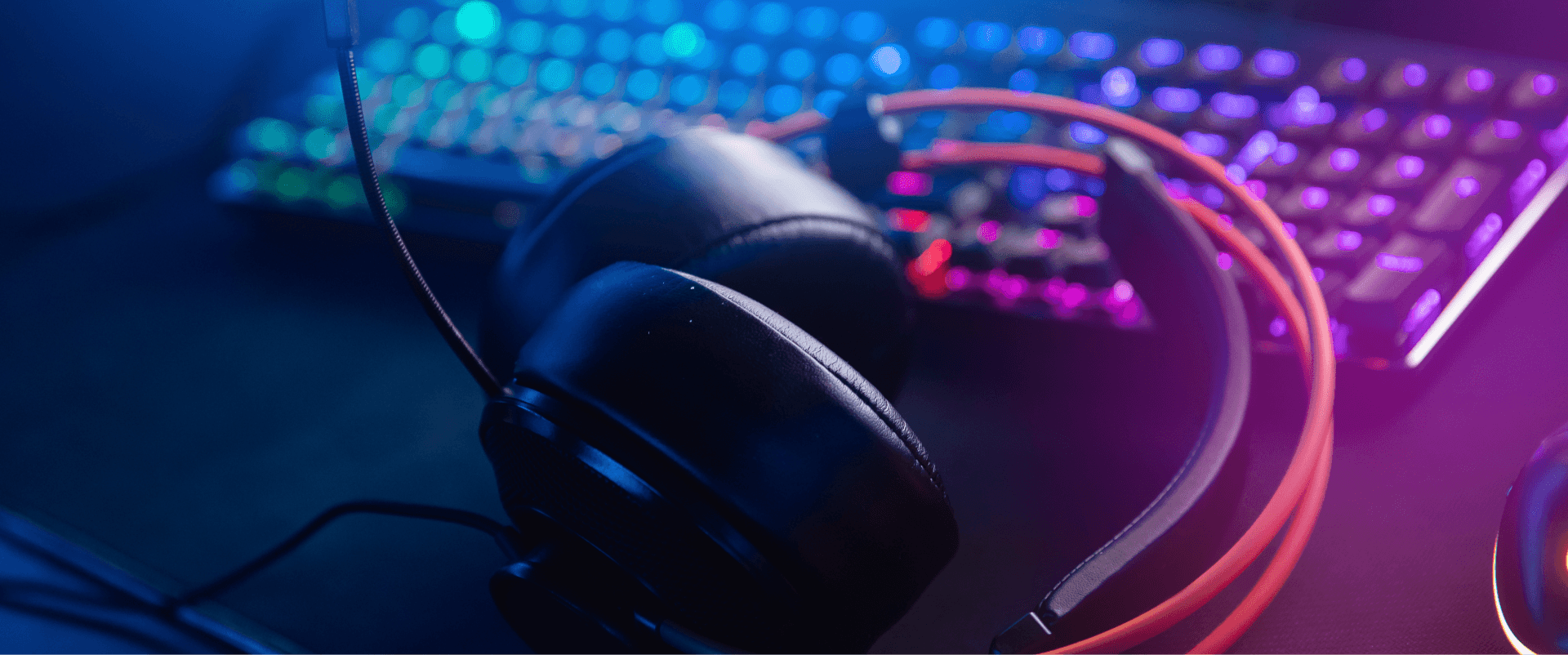 Крупный план игровых наушников и клавиатуры с яркой RGB подсветкой, демонстрирующий аксессуары.